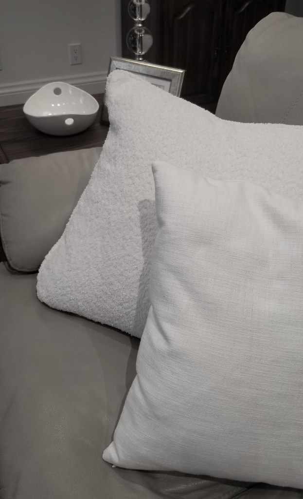 This image shows how boucle and linen pillows add textural contrast to the smooth grainy leather they sit on